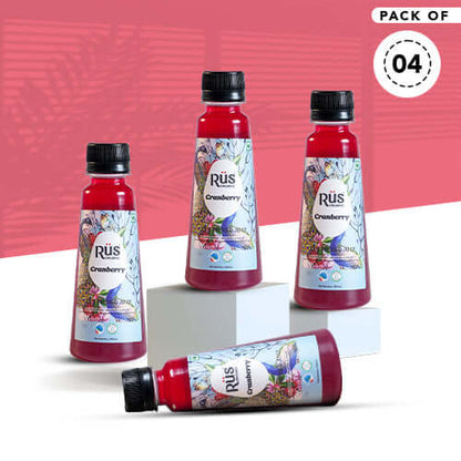 A single, clear plastic bottle filled with red Rus Organic Cranberry Juice. The bottle has a black cap and a colorful label featuring a peacock feather design, cranberries, blueberries, and the "Rūs Organic Cranberry" logo. The background is a solid gray
