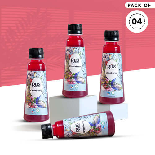A single, clear plastic bottle filled with red Rus Organic Cranberry Juice. The bottle has a black cap and a colorful label featuring a peacock feather design, cranberries, blueberries, and the "Rūs Organic Cranberry" logo. The background is a solid gray